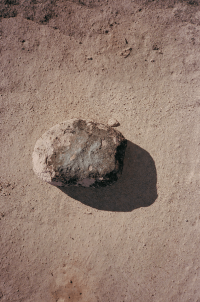 A single weathered stone on red desert sand