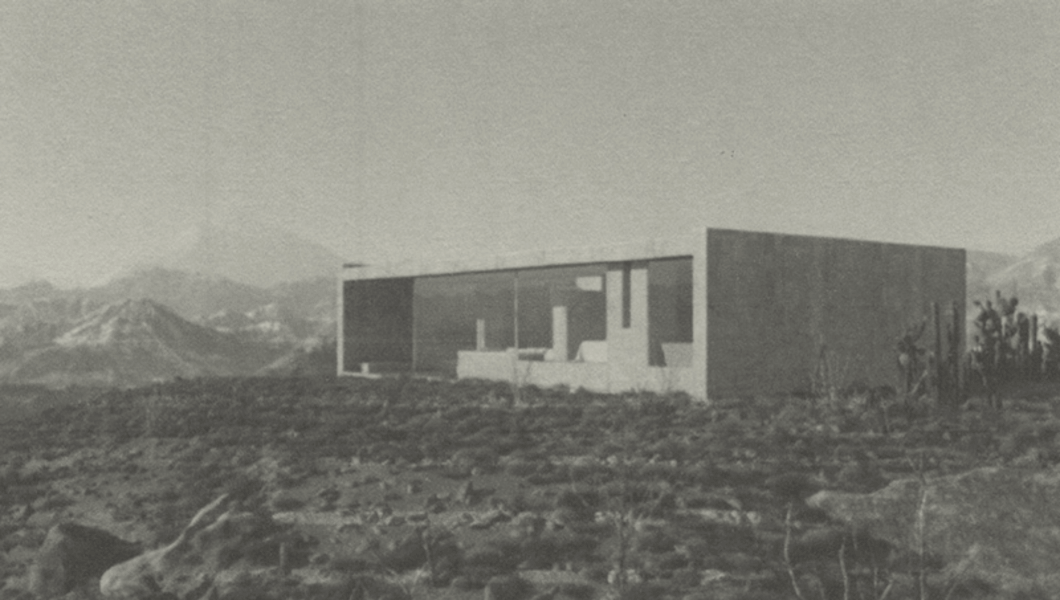 A low monolithic house resting in the raw desert landscape